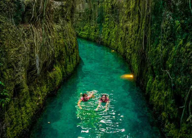Couple swimming in the spectacular subway river of Xcaret Park